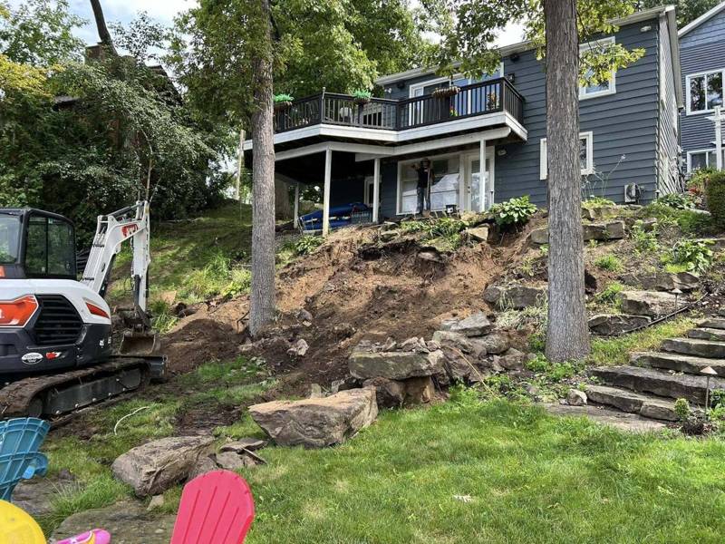 Excavator working on a rocky, wooded hillside