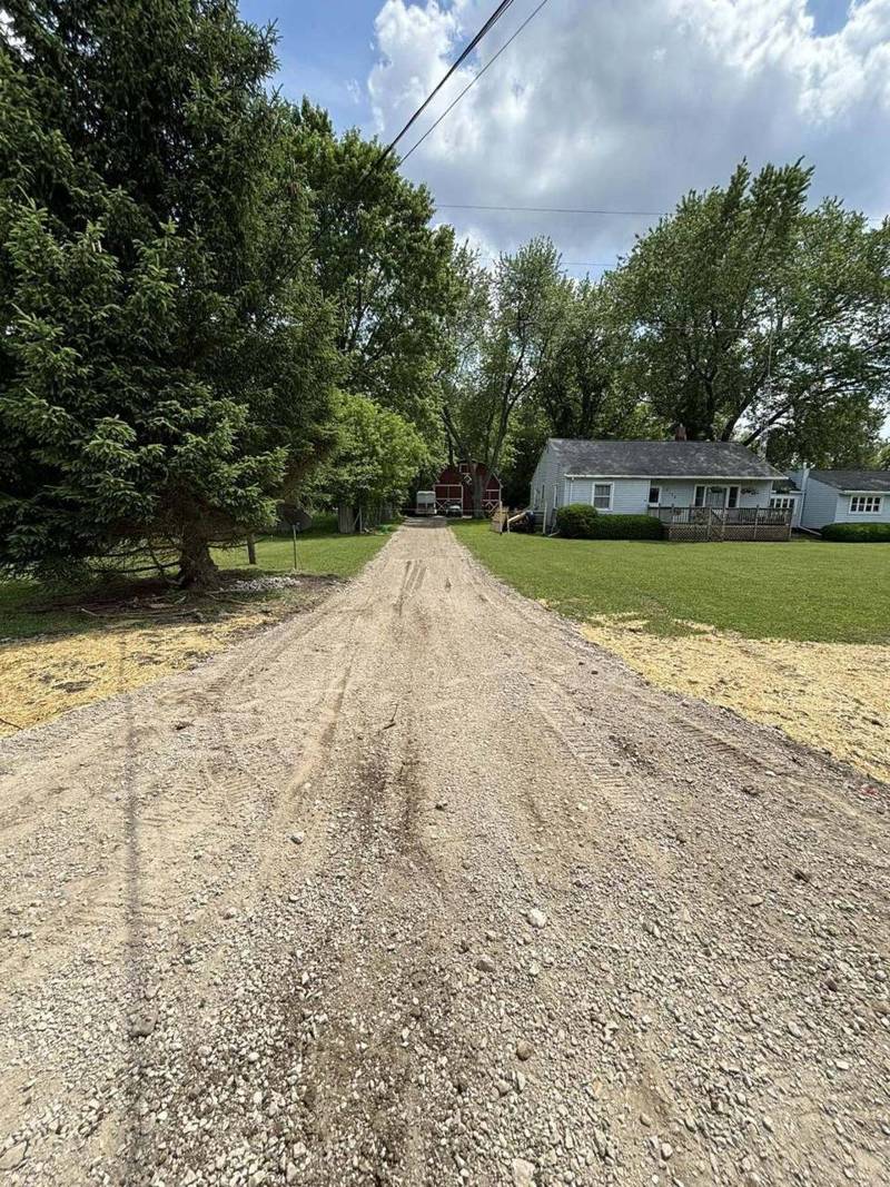 New gravel driveway cut through a wooded lot